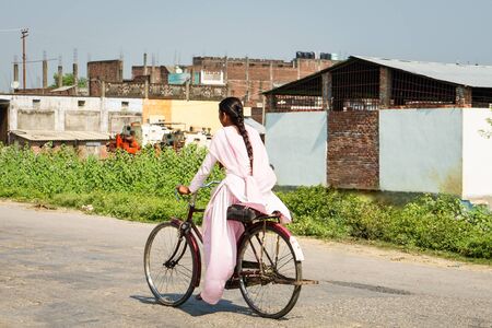 Woman rides bicycle on the road in countryside indiaの写真素材