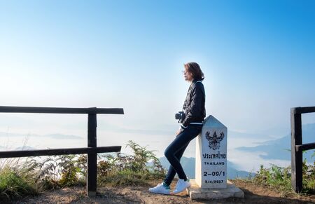 Tourist Asian woman standing with A kilometer stone and beautiful background view. Description Thai...