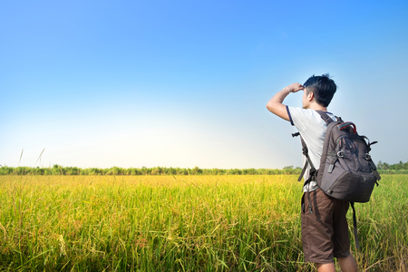 Asian Man backpacker standing and looking rice field with blue sky landscapeの写真素材