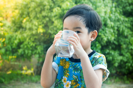 Asian Cute Boy drinking water for Healthy and Refreshing with green tree background.の写真素材