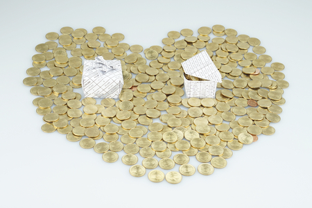 Stack of gold coins put as heart shaped have gift box and house placed on a white table.の写真素材
