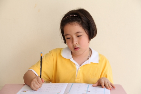 Young attractive female Asian student sitting at her desk and writingの写真素材