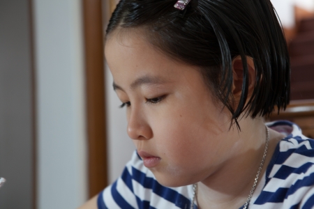 Young attractive female Asian student sitting at her desk and writingの写真素材