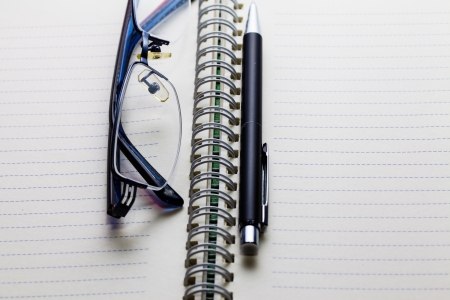 Open notebook with pen and  glasses on a white backgroundの写真素材