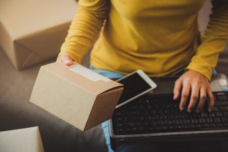Woman holds a box to prepare to deliver to the customer according to the order at home.Work from home and marketing online or startup small business concept.with copy space.の写真素材