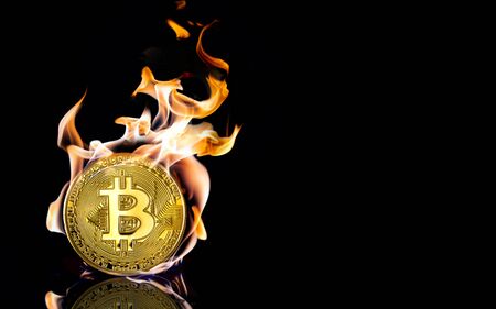 A burnt golden bitcoin on black background with reflection and copy spaceの写真素材