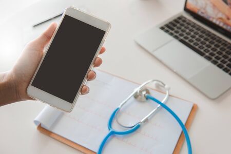 Doctor using mobile phone reading report Treatment on desk.healthcare and technology concept.の写真素材