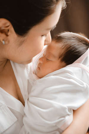 Close-up young woman holding a newborn baby in her arms.の写真素材