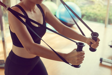 Young woman with perfect body training triceps with cable exercise machine in the gym. Concept...
