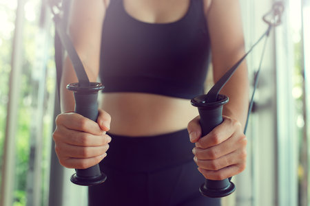 Young woman with perfect body training triceps with cable exercise machine in the gym. Concept...