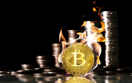 Bitcoin inside the fire on the background of coins of baht. Finance and investment concept.の写真素材