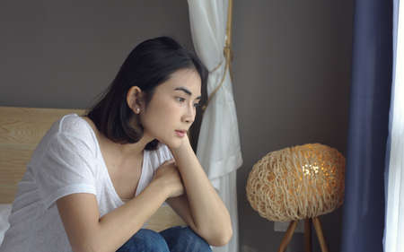 Sad thoughtful young woman pensive face looking away thinking of problems sit alone at home, feels...