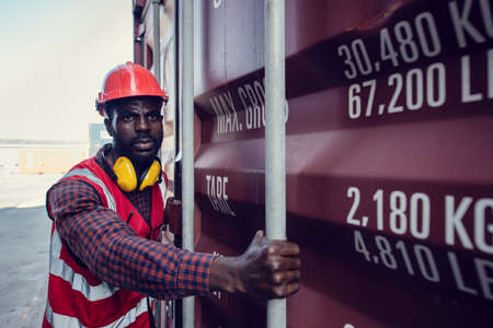 African-American  workers are opening containers for inspection and check that repairs have been completed in containers.の写真素材