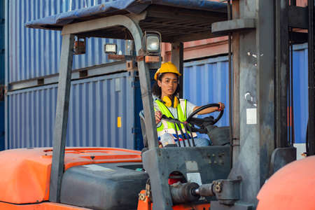 Female foreman is driving forklift at shipping container yard. shipping in docks.