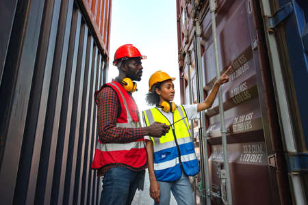 Two African american male and female worker check and control loading freight containers from Cargo...