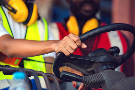 Two African American male and female worker in uniform and helmet driving and operating on diesel...
