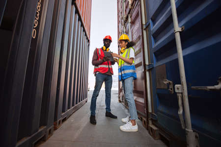Two African american male and female worker using tablet and checking control loading freight...