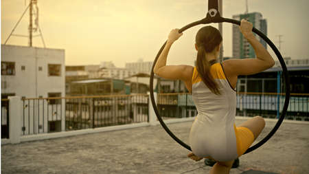 Woman in sportswear doing sky yoga on the rooftop in the evening when the sun set. Self care and health concepts.の写真素材