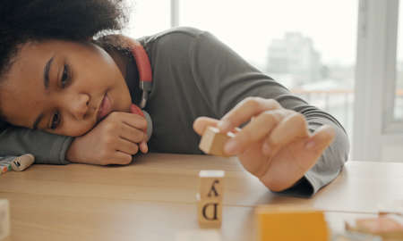 African American student doing activity playing block wooden for development together in the classroom.の写真素材