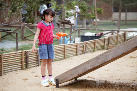 Little girl using water guns to spray wooden slider in the playground.の写真素材