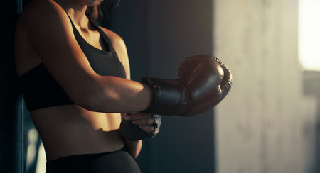 Close-up young woman wearing boxing glove in the gym.の写真素材