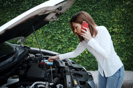Woman using mobile phone calling for assistance after a car breakdown on street.