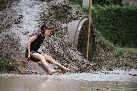 Little girl has fun with soil and mud slider in public playground and show happiness with smiling.の写真素材