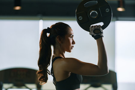 Sporty woman exercising with weight plate in the gym.の写真素材