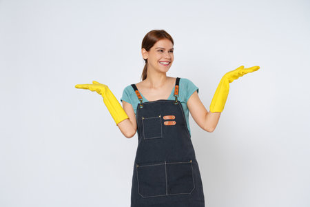 Young woman wearing yellow rubber gloves presenting or showing open hand palm with copy space for product isolated on white background.の写真素材