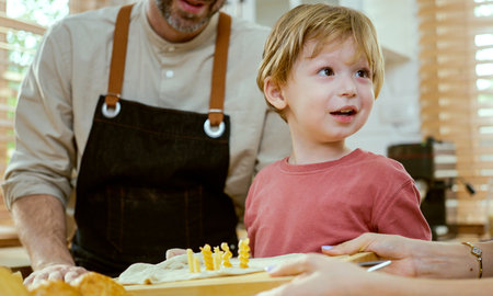 Happy young family enjoying making pie dough or pastries in modern kitchen together, very happy parents teaching little son how to cook bakery at home.の写真素材