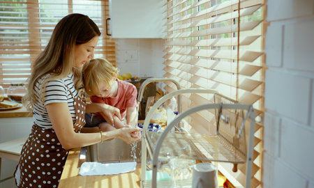 Mother and child wash your hands thoroughly in the sink before entering the kitchen.の写真素材