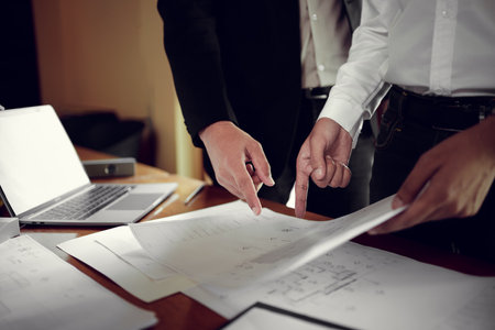Two engineers pointing at drawings project, Architect team meeting consult and work for architectural construction project working with partner and engineering after editing on blueprint paper plans.の写真素材