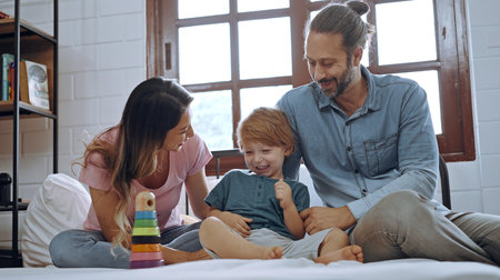 Happiness son playing toy with mother and father on bed, enjoy relaxing together at home.の写真素材