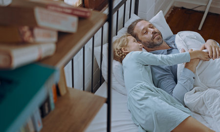 Daughter wakes up father at the bed in the morning.の写真素材