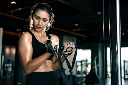 Sporty woman exercising on multistation at gym for arm and shoulders muscles. Fitness exercising in gym.の写真素材