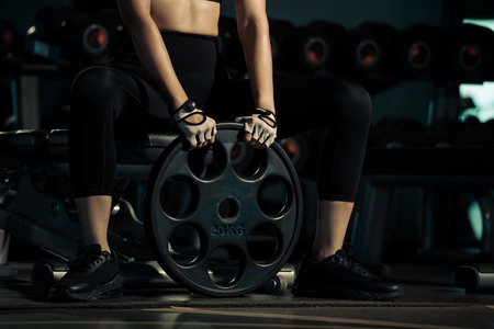 Sporty woman doing exercises with heavy weights plates in gym.の写真素材