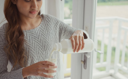 Young woman pouring milk into glass.の写真素材