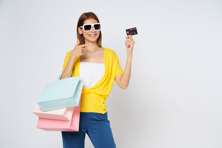 Happy young woman holding shopping bags and showing credit card isolated on white background.の写真素材