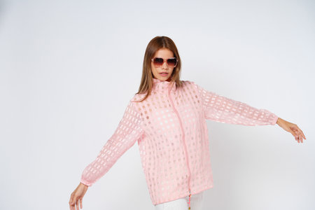 Young woman in pink shirt, wearing sunglasses spreads her arms to the side isolated white background.の写真素材