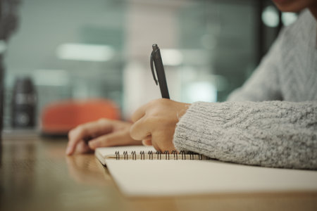 Student preparing for college test, exam, reading book, studying textbook, writing notes, making summary for class report. Learning workplace table, hands with pencil close upの写真素材