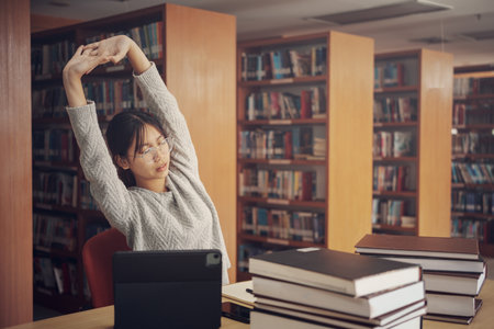 Student girl reading and doing stretch oneself in library of university or colleage.の写真素材