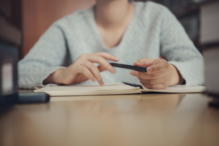 Student preparing for college test, exam, reading book, studying textbook, writing notes, making summary for class report. Learning workplace table, hands with pencil close upの写真素材