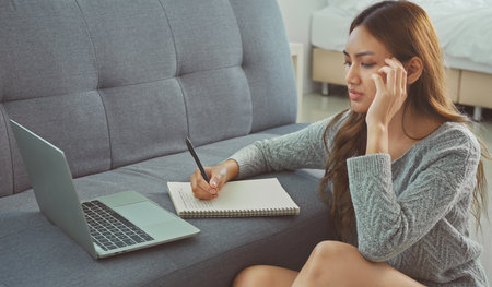 Asian woman sitting on floor holding pen, writing, working from home, noting, writing down, housewife planning week, writing to-do list, student preparing university admissions.の写真素材