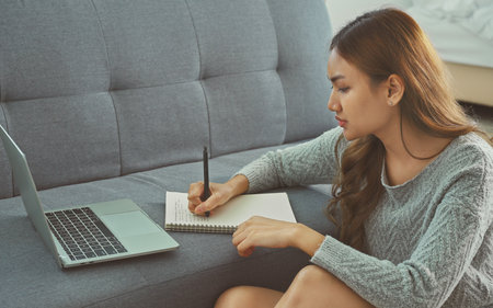 Asian woman sitting on floor holding pen, writing, working from home, noting, writing down, housewife planning week, writing to-do list, student preparing university admissions.の写真素材