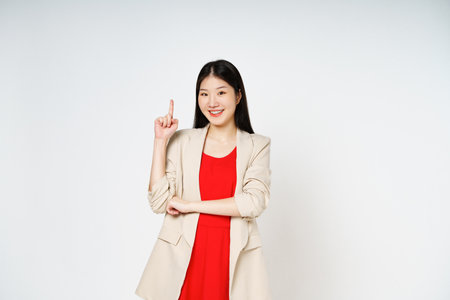Young woman looking at camera and pointing up to copy space with smile face isolated on white background.の写真素材