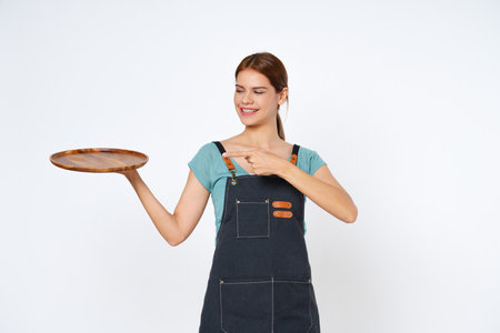 Young woman holding empty plate or dish and pointing isolated on white background.の写真素材