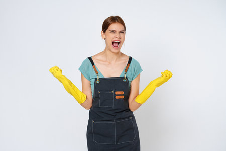 Young woman raise arms wear yellow rubber gloves open mouth isolated on white background.の写真素材
