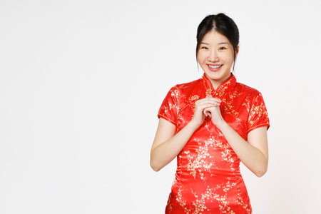 Happy Chinese new year. Asian woman wearing traditional cheongsam qipao dress with gesture of congratulation isolated on white  background.の写真素材