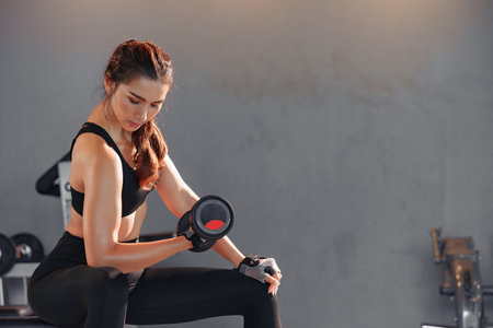 Fitness asian woman doing exercise and lifting dumbbells weights at sport gym.の写真素材