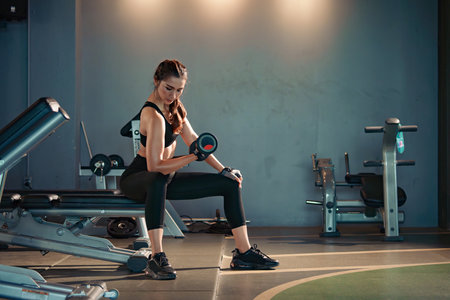 Fitness asian woman doing exercise and lifting dumbbells weights at sport gym.の写真素材